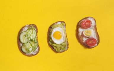  Sandwiches with healthy vegetables, tomatoes, eggs, micro greens on yellow background.