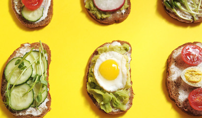  Sandwiches with healthy vegetables, tomatoes, eggs, micro greens on yellow background.
