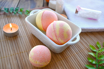 Spa resort setting. Still life image with bath bombs and candle on wooden background. Spring or...