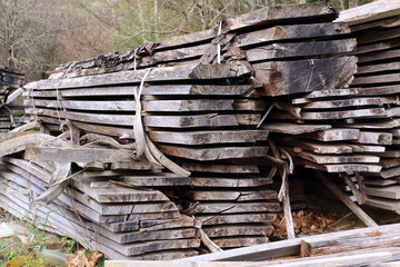 A pile of cut wooden boards outdoors, in front of a sawmill