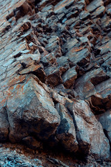 Natural basalt rock with cracks and crevices with a red color coming from iron. Rock wall texture. Graphite stone wall. Stone background. Photography made wit natural daylight. Texture designated for 