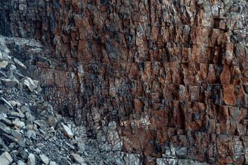 Natural basalt rocky wall with cracks and crevices with a red color coming from iron. Rock texture. Graphite stone wall. Stone background. Photography made with natural daylight. Texture for 3D models