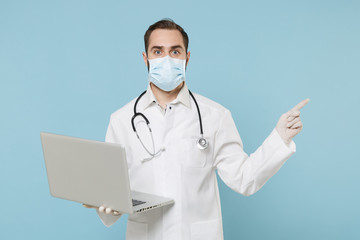 On-line doctor man in medical gown face mask gloves isolated on blue background. Epidemic pandemic...