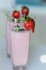 Closeup of strawberry fruit smoothies with strawberry pieces in glass