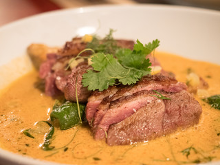 delicious piece of meat with orange sauce on white plate
