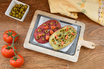 variety of different focaccia, with pumpkin, carrot and beet, on a rustic table