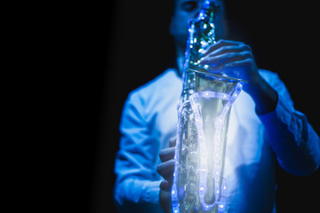 Saxophone musician playing the saxophone in a disco with a sax with led lights.