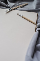 Naklejka premium Blank paper and brushes for painting on blue fabric.