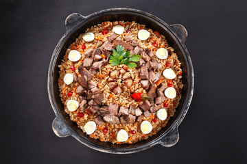 Flat lay pilaf with sliced meat, garlic decorated with quail eggs. Family portion. Uzbek traditional food.
