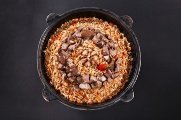 Top view of pilaf in cauldron. Middle asian cuisine.National dish Plov with sliced meat, garlic....