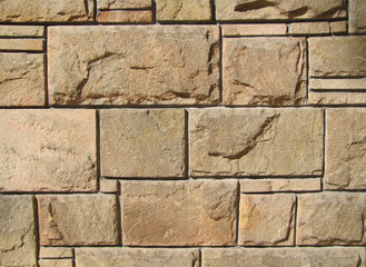 Background natural stone wall rectangular geometric illuminated by the sun.