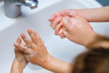 Fototapeta premium Two children, two sisters wash their hands with soap in the sink, protected against viral infection