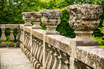 Stone old fence with antique vases on a background of trees