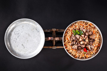 Template with empty dish and plate with pilaf. Promo for your restaurant. Black background. Comparison in rusty weights