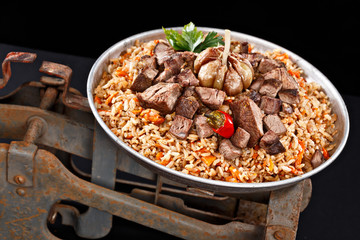 Traditional pilaf on rusty weight. National Uzbek cuisine. Fried rice with sliced meat. Very tasty dish.