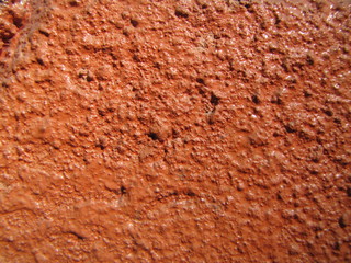 Dark light bright pastel orange red old paint background on rustic surface, natural plaster cement texture in concrete, stuccoed on facade wall in the sun.