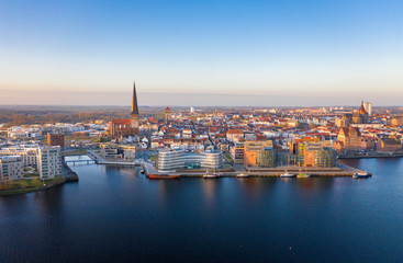 panorama of the city of rostock - aerial view over the river warnow, skyline during sunrise - obrazy, fototapety, plakaty