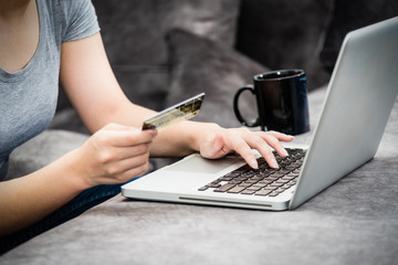 Closeup hand of woman holding SME credit card and using keyboard laptop computer to buy products payment shopping online, spend money, e-commerce, internet banking, working remotely from home concept
