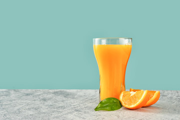 Glass of fresh orange juice with oranges on green-blue background