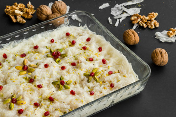 Traditional Turkish Ramadan Milky Dessert ,Gullac designed in glass container on black with walnuts