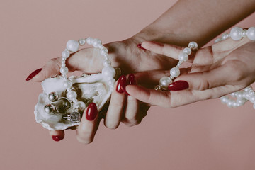 female hand holds oyster shell with pearls from jewelry. Concept poster