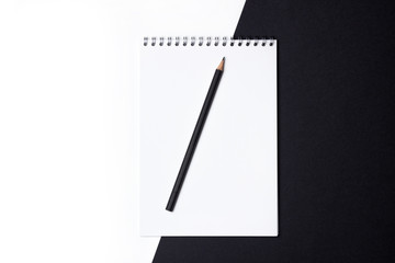 White open blank notebook with black pencil on a black and white background.