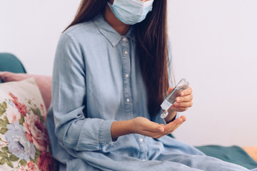 Coronavirus concept. Girl in her home put antiseptic gel on her hands for protection from...