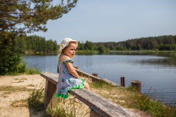 Fototapeta na wymiar girl sitting on the lake, water, forest, summer, July, nature, happy child, vacation