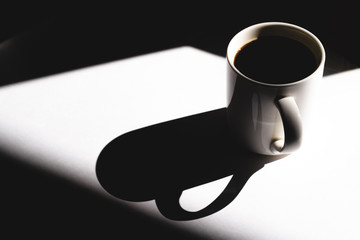 cup of coffee on white background. Cup of fresh hot espresso. sun rays in daylight, hard light and shadows concept.