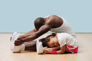 Father and his little daughter stretching knees and backs on the floor