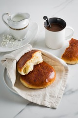 Breakfast with coffee and bun in white cup and plate on marble background. Healthy homemade pastry, copy space
