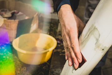 Closeup of a man hand wet sanding a model aeroplane or plastic body. Man holding a 80 grit sanding paper and wet sanding a plastic part.