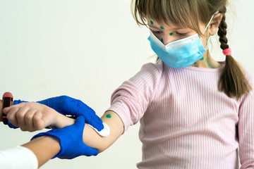 Doctor hands making disinfection preparing hand of child girl for injection wearing blue protective medical mask ill with chickenpox, measles or rubella virus with rashes on body.