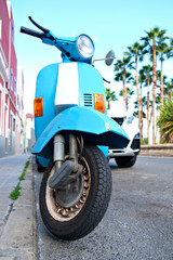 A blue Italian style scooter parked in a street.