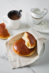 Breakfast with coffee and bun in white cup and plate on marble background. Healthy homemade pastry, copy space