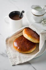 Breakfast with coffee and bun in white cup and plate on marble background. Healthy homemade pastry, copy space