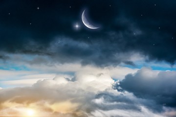 Moon in bright clouds of sunset sun . New moon , moon in the blue sky new moon in the clouds 