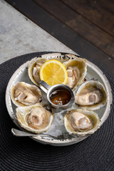 Open oysters with lemon in a white plate.