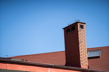 A tall chimney clinker brick built on the roof of a public building.