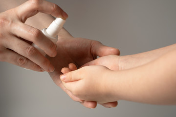 A woman disinfects the child's hands with a disinfectant solution to protect them from viruses and bacteria. The concept of preventing the spread of the virus.