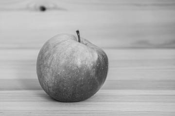 Red fresh apple on wood table. White and black shot.