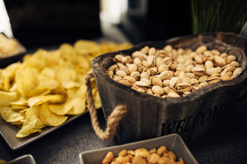 Close up of banquet table with different food Salty snacks. Pretzels, chips, crackers. Walnut, pistachios, almonds, hazelnuts and cashews