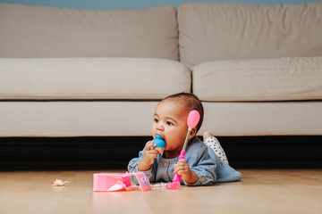 Little infant baby playing on the floor, eating doll head