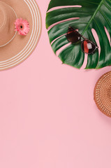 Summer straw hat, tropical monstera leaf, sunglasses, shells, starfish on pink background.