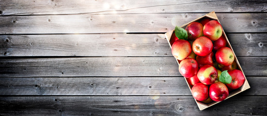 Ripe red apples in wooden box top view on rustic table. Wide apple banner with space for your text