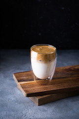 Glass of dalgona coffee on wooden board. Milky cold drink with instant coffee froth 