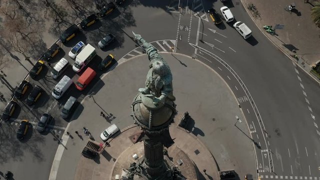 AERIAL: Close up of Columbus Monument in Barcelona, Spain on Beautiful Sunny Day with busy car traffic on Roundabout 