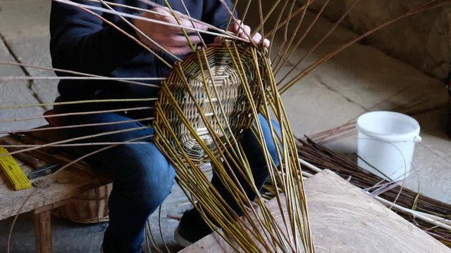 Korbmacher flechtet einen Korb aus Weidenruten