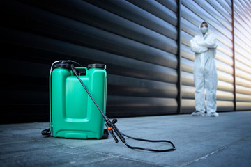 Successful pest control. Exterminator in white protective uniform standing by reservoir with...