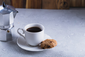 White cup of coffee with oatmeal cookies and coffee maker, breakfast concept, selective focus